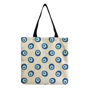 Detail of canvas tote bag featuring repeating blue Nazar eye pattern with black straps
