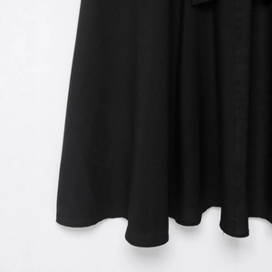 British style black midi trench dress showing elegant woven fabric and wavy hemline detail