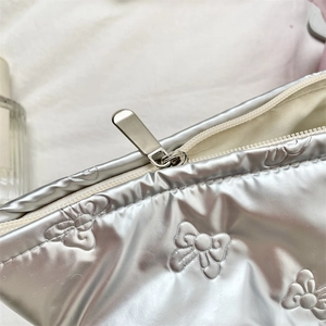 Close-up of metallic silver quilted bag with embossed bow detail and sleek metal zipper