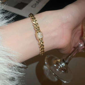 Close-up of 18K gold plated zircon rivet bracelet with textured links on female wrist