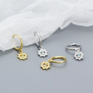 Macro detail of gold and silver devil eye hoop earrings with sparkling zircon star charms
