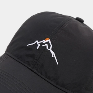 Macro view of mountain embroidery detail and water-resistant mesh fabric on black cap