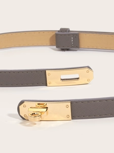 Detail of the iconic gold turn-lock buckle on a grey cross-pattern leather narrow belt
