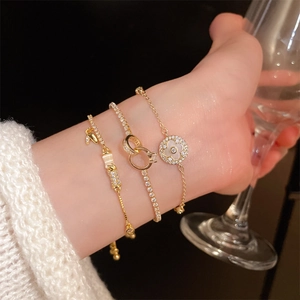 Detailed view of three-piece gold-plated bracelet set with clover charms on wrist