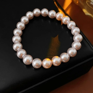 Close-up of pink-white pearl bracelet beads on a black jewelry box with warm lighting