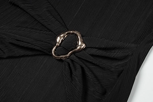 Detail of elegant gold geometric buckle on black pleated fabric of a sexy waist dress