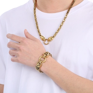 Detail view of gold hip-hop skull necklace and bracelet set worn on a white t-shirt