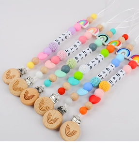 Collection of colorful silicone and beechwood baby pacifier clips with rainbow charms