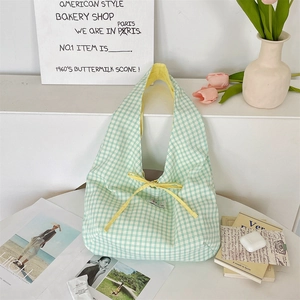 Close-up of green checkered tote bag with a yellow bow decoration and soft cotton canvas texture