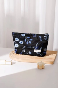Close-up of blue floral embroidery on a black cotton linen makeup bag with H&R label