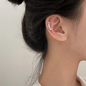 Detailed view of elegant silver ear cuff featuring five round white pearls on a model ear