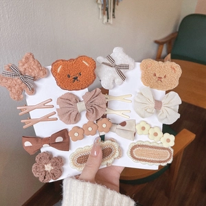 Detail of cute bear and flower plush hair clips set in brown and beige tones