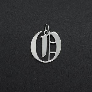 Macro shot of silver Gothic letter D pendant with connector ring on black texture