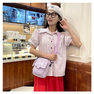 Lifestyle view of a cute purple canvas crossbody bag with white bow knot on flap