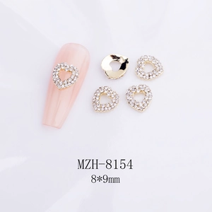 Vue macro de breloques ongles cœur 3D 8x9mm évidées avec base dorée et strass