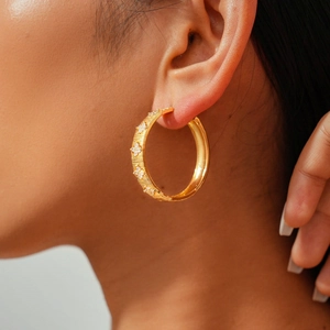 Close-up of 18k gold plated hoop earring with zircon flowers and brushed texture finish