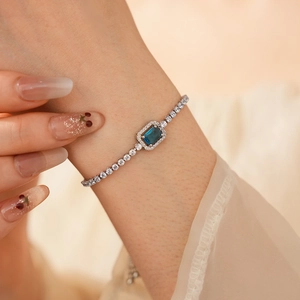 Detailed close-up of a silver pull-string bracelet with square blue zircon and pavé stones