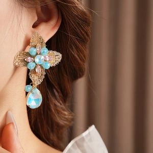Detailed shot of vintage gold flower earrings with blue and pink crystals on a model