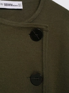 Detail einer dunkelolivgrünen Strickjacke mit Knöpfen und Marken-Größenetikett