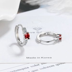 Detail of silver hoop earrings featuring oval red zircon and white diamond accents