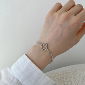 Detailed close-up of a silver clover bracelet with sparkling zircons worn on a wrist
