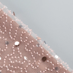 Close-up of pink mesh fabric with intricate beadwork and shimmering sequins detail