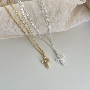 Close-up of gold and silver sterling silver cross necklaces with sparkling zircon inlay