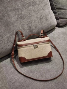 Detail of a beige canvas and brown leather box bag on a textured grey surface