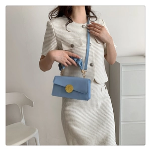 Gros plan du sac à main bleu clair à poignée plissée avec boucle dorée et bandoulière