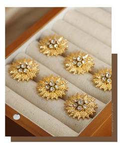 Close-up of gold flower earrings with zircon inlay in a wooden jewelry box