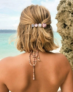 Detail shot of a candy-colored hair clip with four round resin pearls on blonde hair