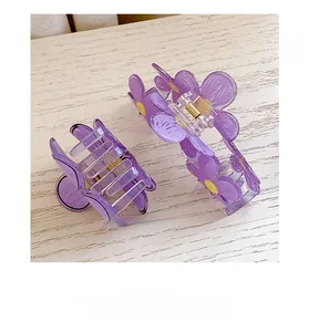 Close-up of two purple floral hair claws with yellow centers on a white wood surface