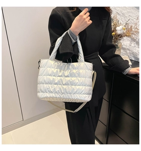 Detail of silver quilted tote bag showing metallic texture and wide padded handle