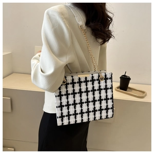 Classic black and white tweed shoulder bag with gold chain strap in minimalist room