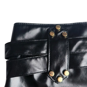 Nahaufnahme der schwarzen PU-Ledershorts mit Goldnieten und Schnürung im Detail