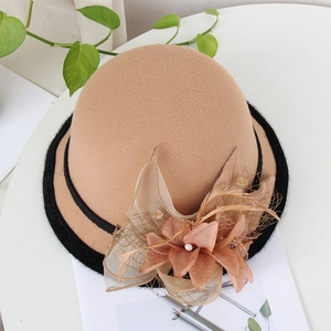 Detail of camel wool felt bowler hat with mesh veil, feathers and floral accents