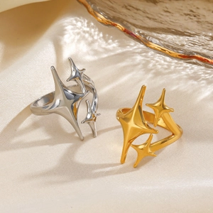 Polished stainless steel star open rings in gold and silver on cream silk background