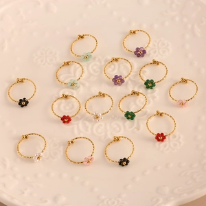 Minimalistisches Gold-Blumenring-Set mit bunten Natursteinen auf einem weißen Teller