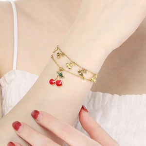 Detail of a double-layer 18K gold chain with a vibrant red enamel cherry pendant charm
