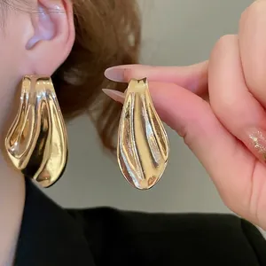 Abstract wave earrings in gold finish with a fluid liquid metal texture for women
