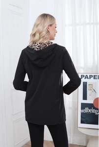 Detail of hood with leopard animal print lining on a long black zip-up jacket