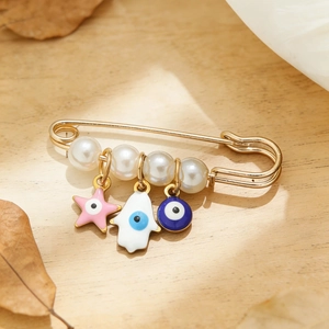Détail de l'épingle Evil Eye avec main de Hamsa, étoile rose et breloques en perles blanches