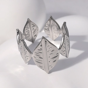 Macro shot of silver stainless steel leaf ring with detailed engraving on white background