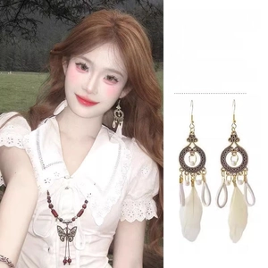 Detail of vintage flower metal base earrings with white feathers and beaded accents