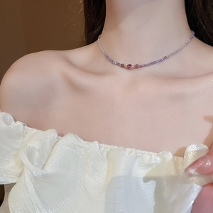 Close-up of a delicate purple zircon beaded necklace worn on a woman's collarbone