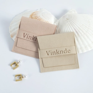 Détail de pochettes à bijoux en daim microfibre rose et beige avec une boucle d'oreille