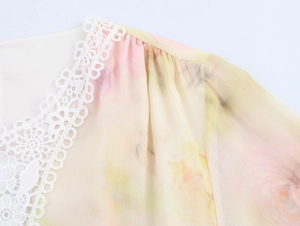 Dettaglio dello scollo a V in pizzo bianco su abito in chiffon floreale giallo