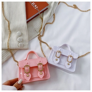 Close-up of pink and lavender mini jelly bags with metal chains on white texture