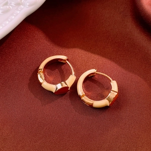Close-up of golden vintage heart hoop earrings with cream enamel on red silk