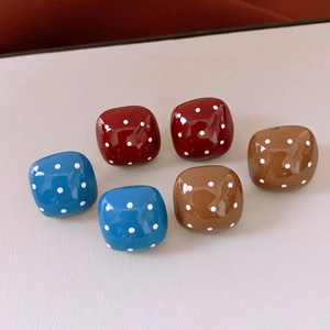 Close-up of square polka dot resin stud earrings in blue, burgundy and brown colors